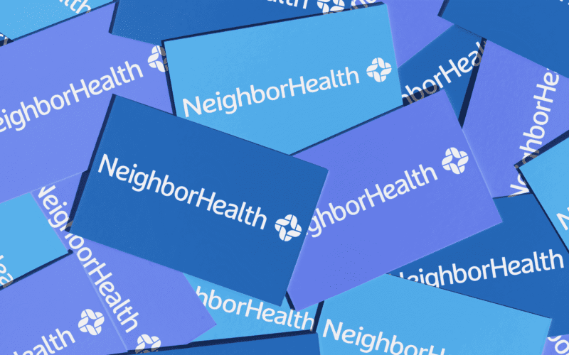 A pile of overlapping business cards displaying the "NeighborHealth" logo in white text on varying shades of blue backgrounds.