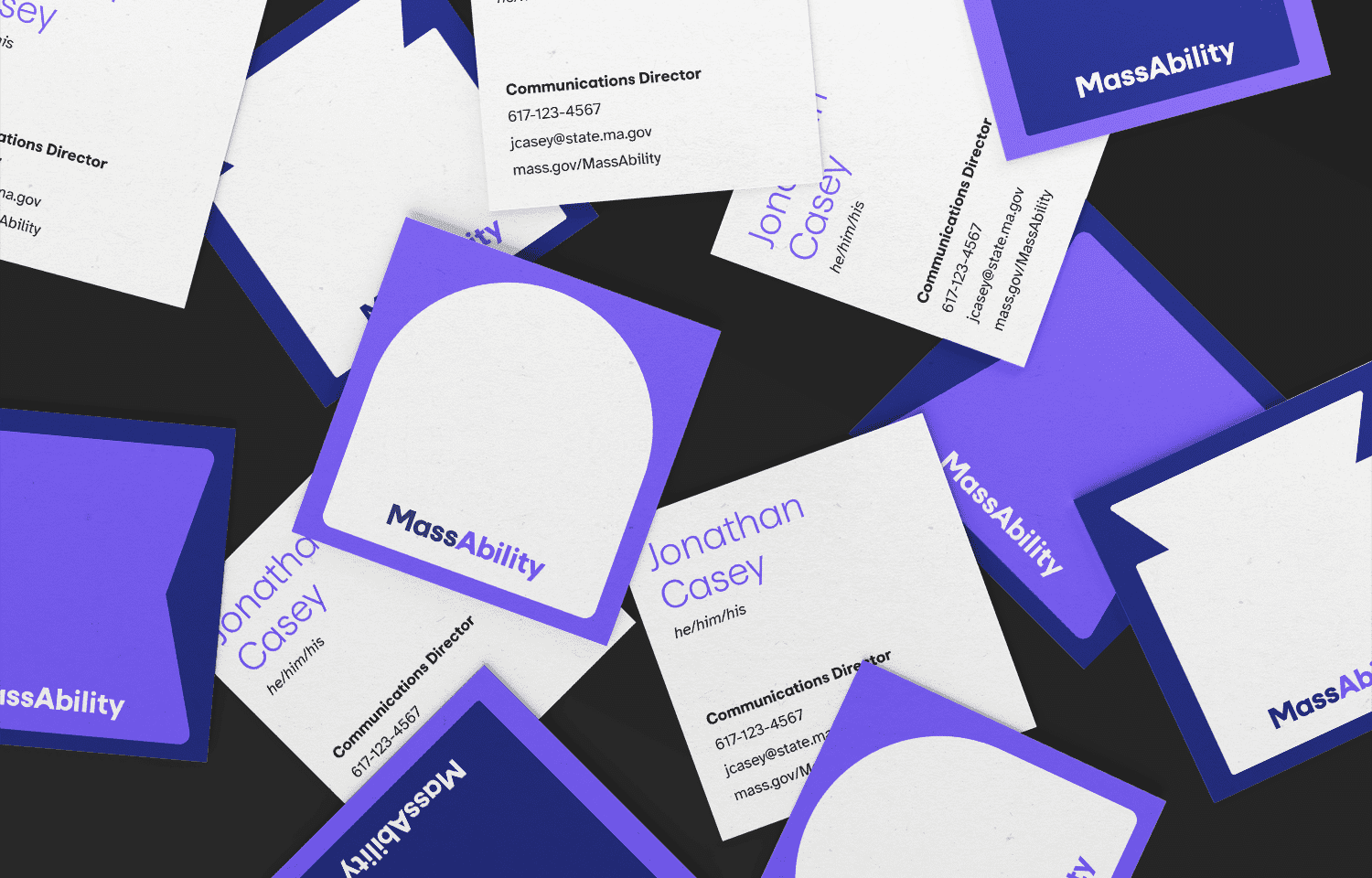 A scattered collection of business cards and square cards, featuring the name Jonathan Casey and MassAbility branding, in shades of purple, blue, and white, on a black background.